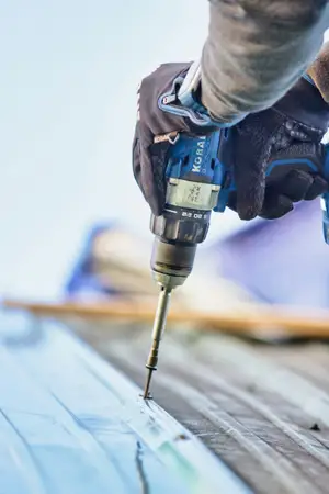 Roofers working on a roof, fixing panels down by hand