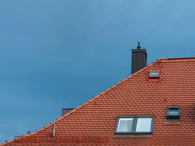 Character home's tiled roof and chimney against an evening sky